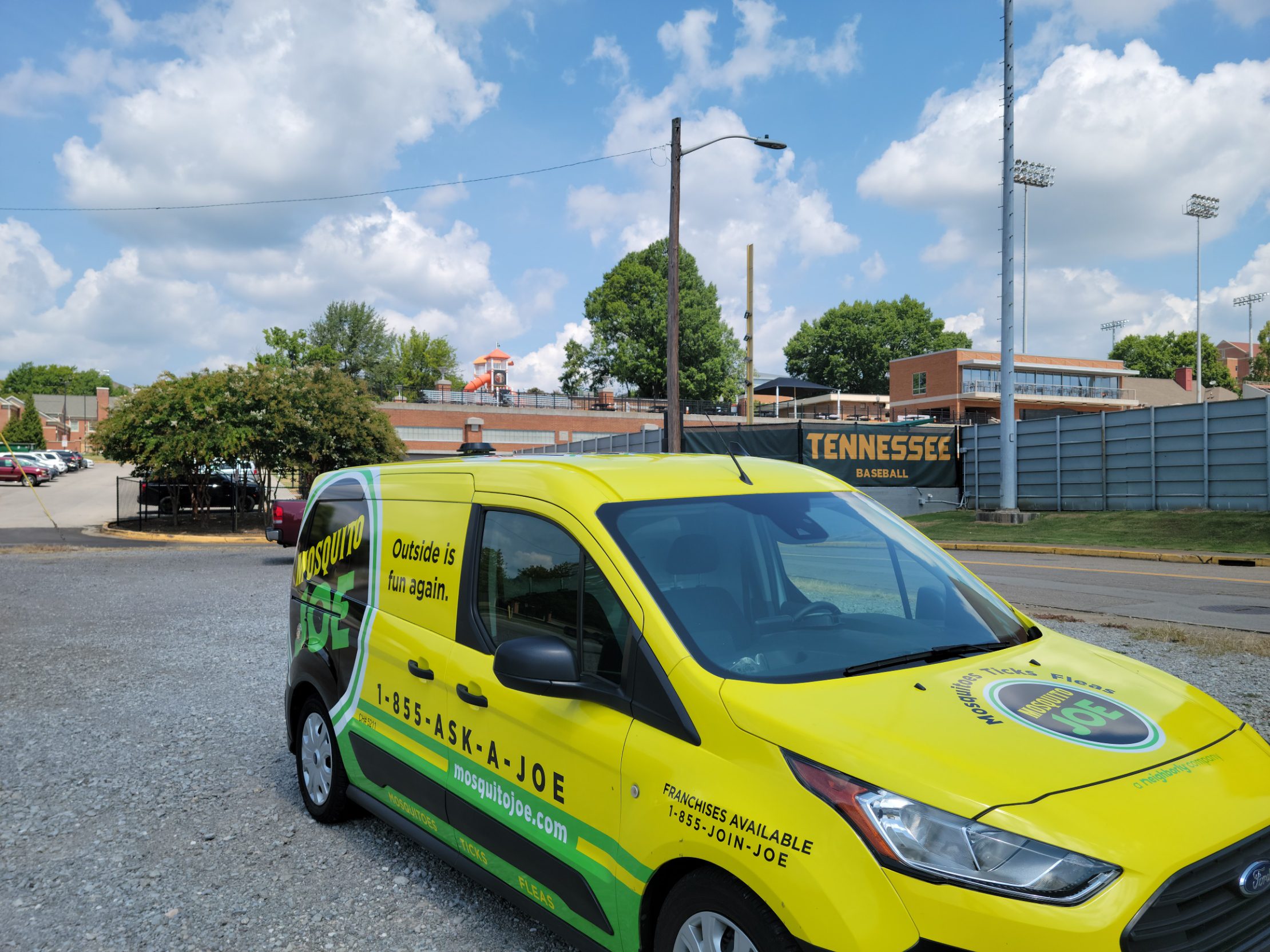 Yellow and green service van parked at University of Tennessee Baseball Facility